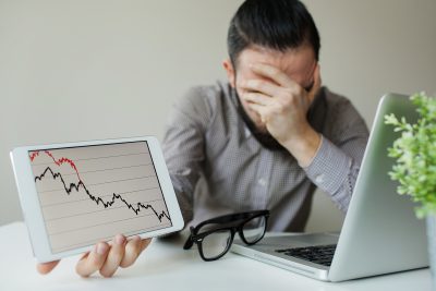 Depressed businessman leaning head below bad stock market